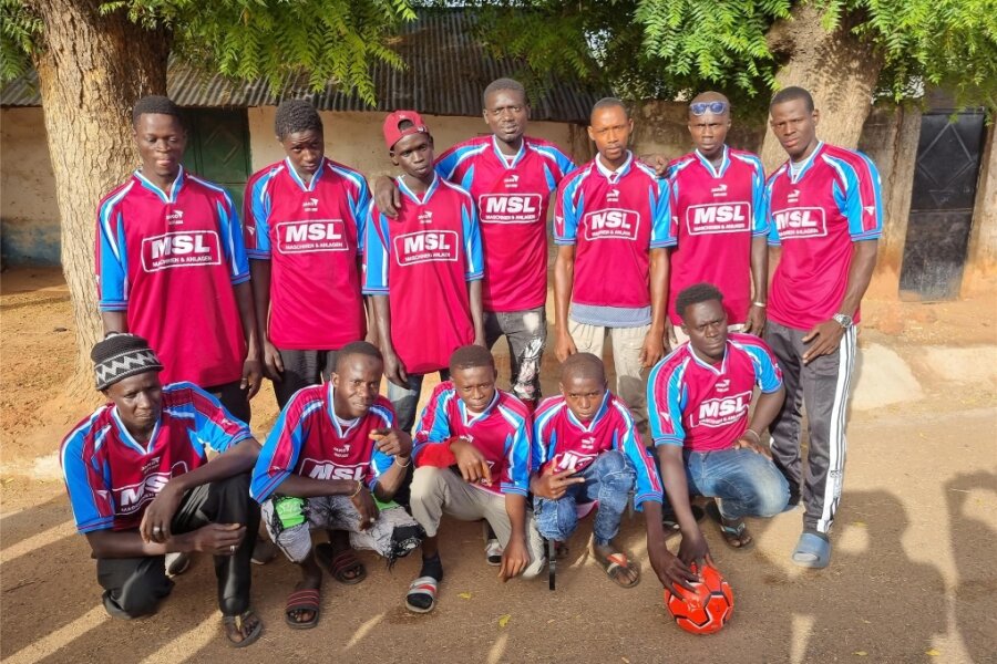 Warum eine Fußball-Mannschaft in Gambia mit Trikots des TSV Falkenau spielt - Anstoß in rot-blau: Die Fußballer aus Ngayen Sanjal in Gambia sammeln Meisterschaftspunkte in den Trikots des TSV 1888 Falkenau. Heike Gärtner und Jürgen Müller haben kürzlich die Trikot-Spende und einen signierten Ball übergeben.