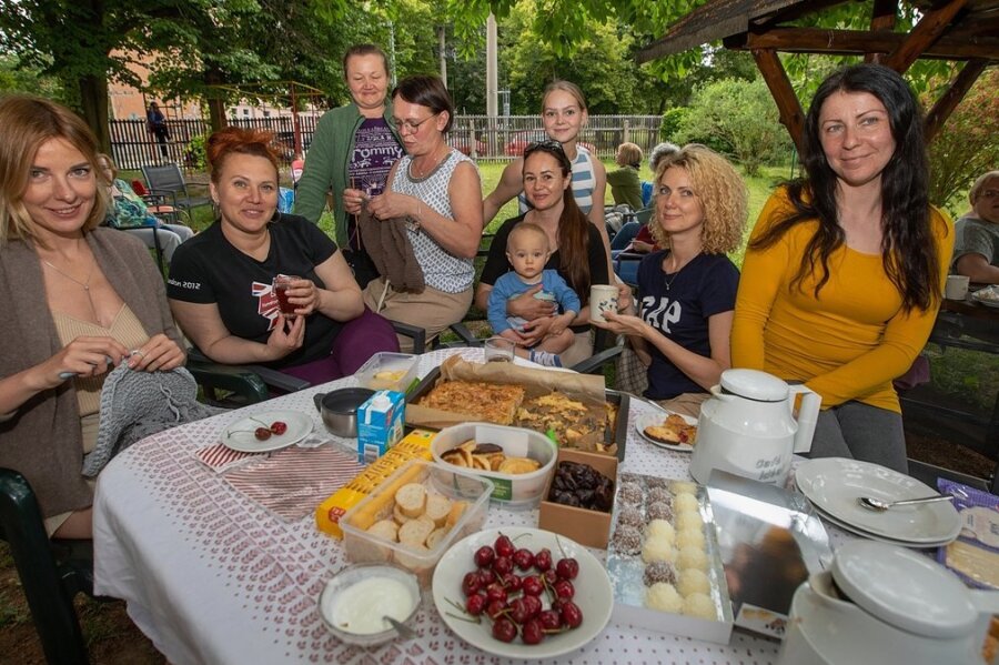 Olga Kotov (Mitte, mit Strickarbeit) übersetzt mit Tochter Sophie (hinten) für die Ukrainerinnen im Paulushaus. Bei einem Strick-Picknick kamen die Frauen im Garten bei Kuchen und Piroschki zusammen.
