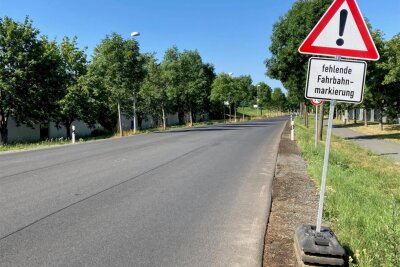 Warum eine Staatsstraße in Oelsnitz acht Monate lang nicht markiert ist - Im Oelsnitzer Industriegebiet Johannisberg weisen Warnschilder auf die fehlende Straßenmarkierung hin.