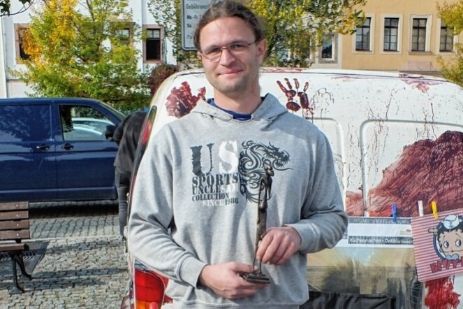 Warum gehen Menschen in Rochlitz auf den Flohmarkt? - Nick Große hat ein ganzes Sammelsurium zum Flohmarkt mitgebracht, darunter eine afrikanische Bronzeskulptur, die er in der Hand hält.