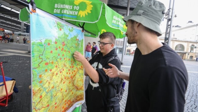 Warum Jung und Alt das 9-Euro-Ticket vermissen werden - Lukas Rietzschel (links) ist Fan des 9-Euro-Tickets und markiert auf der Deutschlandkarte am Stand der Bündnisgrünen mit Mitarbeiter Konstantin Scheffler am Hauptbahnhof, wohin er mit der Fahrkarte gereist ist. 