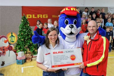 Warum Lebensretter eine Glauchauer Schule auszeichnen - Lehrerin Anja Haberkorn und DLRG-Landespräsident Andreas Lorenczat freuen sich mit Maskottchen Nobbi über den Förderpreis.