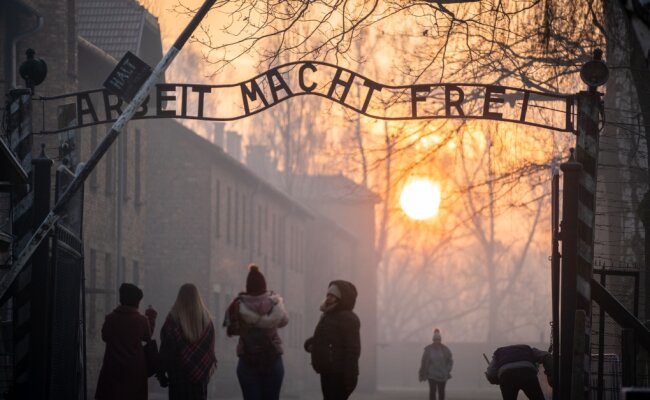 Besucher stehen am frühen Morgen am Tor zum früheren Konzentrationslager Auschwitz I mit dem Schriftzug "Arbeit macht frei".