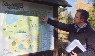 Was 2022 im Stadtpark gebaut werden soll - Der Fachbereichsleiter für Stadtentwicklung, Michael Claus, zeigt an einer Informationstafel im Stadtpark, in welchem Teil der Anlage Ende März die Arbeiten an den Wegen beginnen sollen.