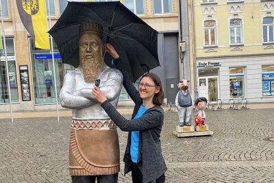 Was es mit der neuen Holzfigur auf dem Plauener Postplatz auf sich hat - Mit einem Schirm wurde am Freitag die Holzfigur auf dem Postplatz vor dem Regen geschützt.