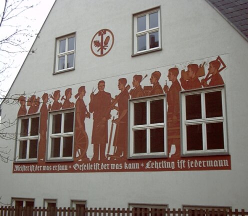 Der Wandfries am Beruflichen Schulzentrum Reichenbach stellt verschiedene Gewerke dar. Darunter steht: "Meister ist, der was ersann. Geselle ist, der was kann. Lehrling ist jedermann." 