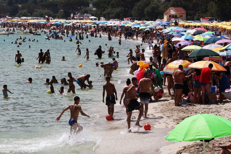 Was Urlaubsländer beim Klimaschutz planen - Zahlreiche Menschen sind am Strand von Mondello auf Sizilien zu sehen. Italien leidet besonders unter Übertourismus.