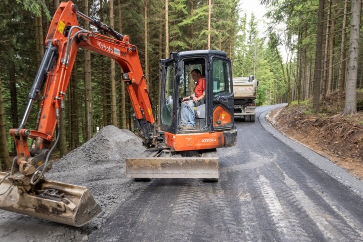 Ein Abschnitt des Bärenfangwegs nahe Oberwiesenthal hat in den vergangenen Tagen eine neue Asphaltdecke erhalten. Das Foto zeigt Steffen Schreier bei Anpassungsarbeiten zur Anbindung eines anderen Waldwegs. 