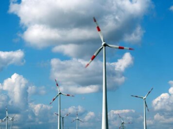 Weiterer Windpark geplant - Windräder drehen sich unter dem Wolkenhimmel auf einem Feld.