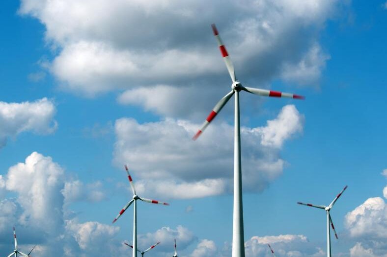 Weiterer Windpark geplant - Windräder drehen sich unter dem Wolkenhimmel auf einem Feld.