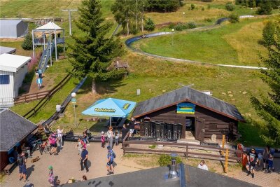 Weniger Urlauber im Erzgebirge als im vergangenen Sommer - Zu beliebten Ausflugszielen in Oberwiesenthal gehören die Sommerrodelbahn (vorn) und die "Fly-Line" (links oben), bei der sich Besucher mit einem Sicherheitsgurt in eine Art Fahrbahn einhängen, auf der sie in luftiger Höhe ins Tal sausen.