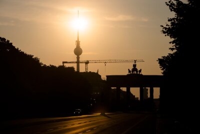 Wetterdienst erwartet Sommer-Intermezzo - Das Brandenburger Tor und der Fernsehturm sind im Gegenlicht der aufgehenden Sonne zu sehen. Am Montag zeigt sich laut Vorhersage meist die Sonne, höchstens wird es locker bewölkt.