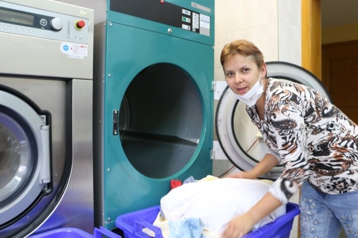 Wie behinderte Menschen ihren Traumjob finden - Renata Fülöp-Szin leert die Waschmaschine mit der gewaschenen Wäsche. Über ein Praktikum fand die 39-Jährige diesen Job. 
