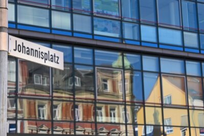 Wie die Innenstadt vom Limbach-Oberfrohna lebendiger werden soll - Häuser am Johannisplatz in Limbach-Oberfrohna spiegeln sich in einer Glasfassade. Die Stadt will ihr Zentrum mit verschiedenen Ideen auch mit Blick auf das Kulturhauptstadtjahr 2025 in Chemnitz weiter aufwerten. 