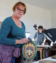 Wie die Zünfte ihre Särge schmückten - Restauratorin Annegret Michel zeigt das Schild der Schuhmacher. Im Hintergrund fotografiert Volker Distel. 