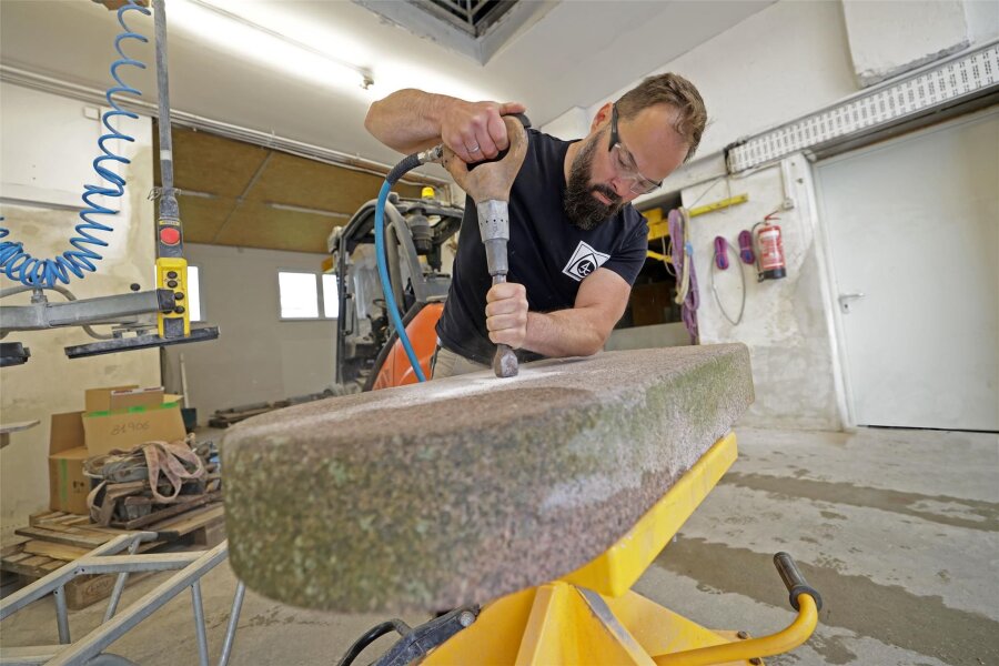 Wie ein westsächsischer Steinmetz Grabsteine rettet - Erik Jorra arbeitet in seiner Werkstatt einen alten Grabstein auf. Per Presslufthammer wird zunächst die Inschrift entfernt.