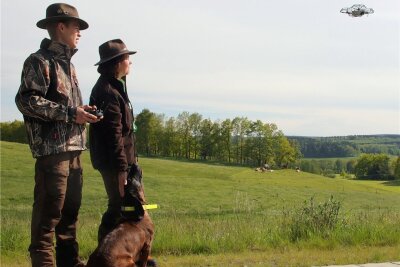 Wie im Vogtland Rehkitze vor dem Mähtod gerettet werden - Vom Rand der Grünfläche aus beobachten Carljohannes und Kathleen Rotter, wie ihre Drohne die Wiese überfliegt, um versteckte Rehkitze ausfindig zu machen. 