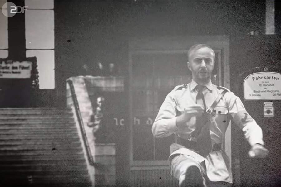 Jan Böhmermann erklärt in Nazi-Uniform, warum Schwarzfahren in Deutschland eine Straftat ist. Im Hintergrund: ein Blick in den Zwickauer Hauptbahnhof aus dem Jahr 1935. 