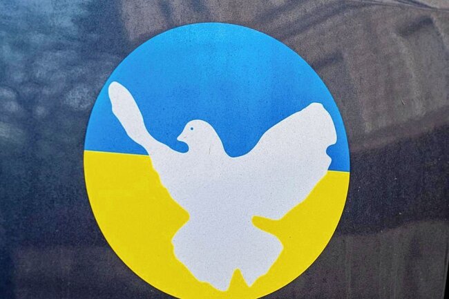Wie Sahra Wagenknecht den SPD-Friedensappell findet - Ein Aufkleber in den Farben der Ukraine und das Friedenstauben-Symbol kleben auf einer Heckklappe eines Autos. Der Weg zum Frieden bleibt auch in Deutschland umstritten. 