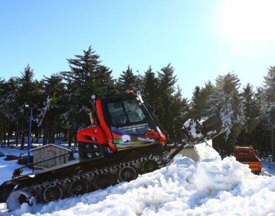 Am Anfang wird der Schnee mit Lkw antransportiert, danach mit dem Pistenbully zu einem Berg aufgeschoben. 