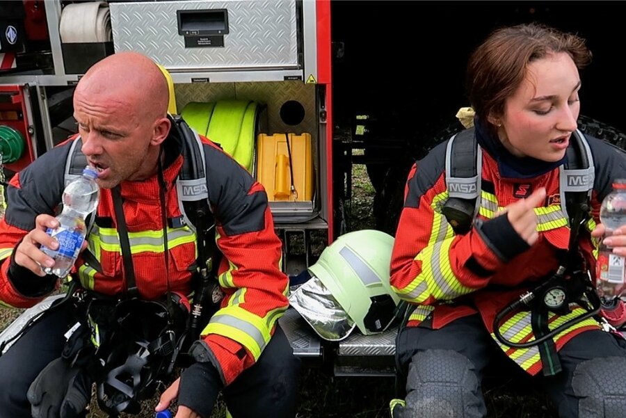 Wie sich die Feuerwehrleute im Erzgebirge auf Hitze-Einsätze vorbereiten - Markus Herzog und Emily Baersch haben nach dem Einsatz einen kräftigen Schluck aus der Wasserflasche nötig.