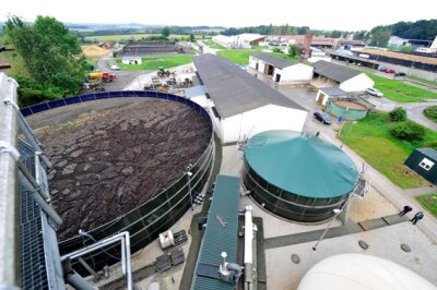 Wie wird aus Biogas Strom und Wärme produziert? - Blick auf den Behälter für Rest-Gülle (links), den Container mit dem Generator (Mitte) und auf Zwischenspeicher