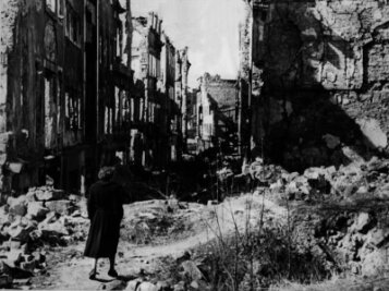 "Wir hörten die Kaninchen jammern" - Eine Frau geht in einer Straße in Dresden an Häusern vorbei, von denen nach dem Zweiten Weltkrieg nur noch Ruinen geblieben sind. Knapp drei Monate vor Ende des Zweiten Weltkriegs legten britische und amerikanische Bomber am 13. und 14. Februar 1945 Dresden in Schutt und Asche.