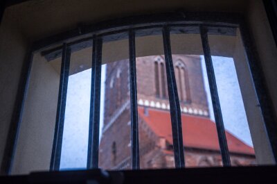 Wismar: Im "Kittchen" sind bald Zimmer frei - Durch ein vergittertes Hotelzimmerfenster in der ehemalige Jugend-Arrestanstalt können nach dem Umbau zum Hostel "Das Kittchen" Übernachtungsgäste zum St. Marienkirchturm schauen.
