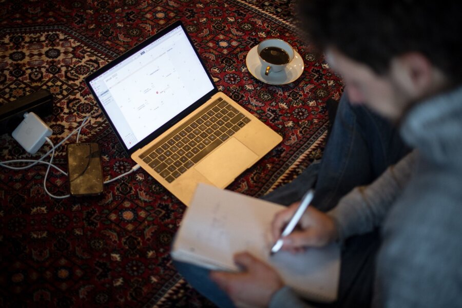 Wochenarbeitszeit in Sachsen höher als bundesweit - Ein Mann sitzt im Homeoffice mit Laptop auf dem Teppich und arbeitet.
