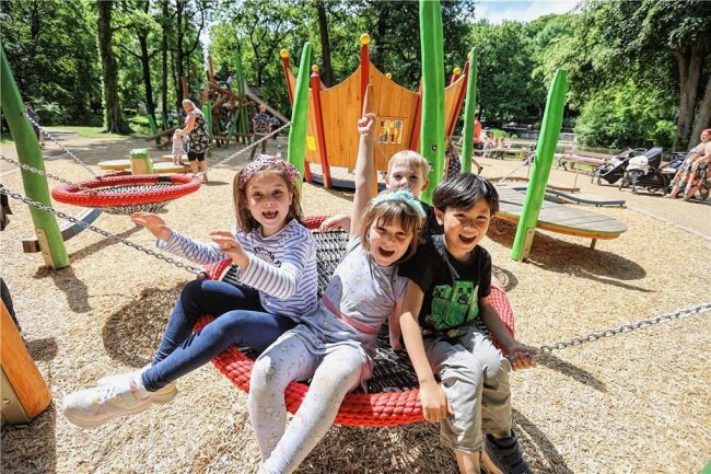 Womit der neugestaltete Spielplatz am Chemnitzer Schloßteich punktet - Alisia, Chiara, Matz und Vincent (von links) in einer der Nestschaukeln auf dem neugestalteten Spielplatz auf der Schloßteichinsel. Hinter ihnen steht die begehbare Krone mit Dreh- und Klangspielen. 