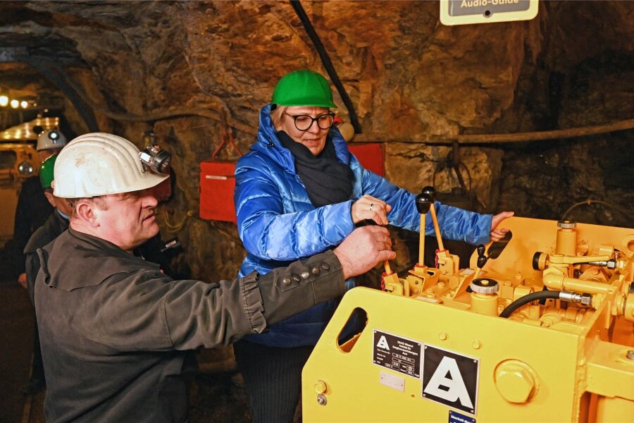 Zeitzeugnis der Wismut kehrt im Erzgebirge ins Bergwerk zurück - Einweihung eines Bohrwagens für den Welterbestandort Markus-Röhling-Stollen Frohnau. Staatsministerin Barbara Klepsch darf den Hebel der wieder aufgearbeiteten Maschine bedienen. Michael Rümmler gibt Hinweise zur Handhabung der Technik.