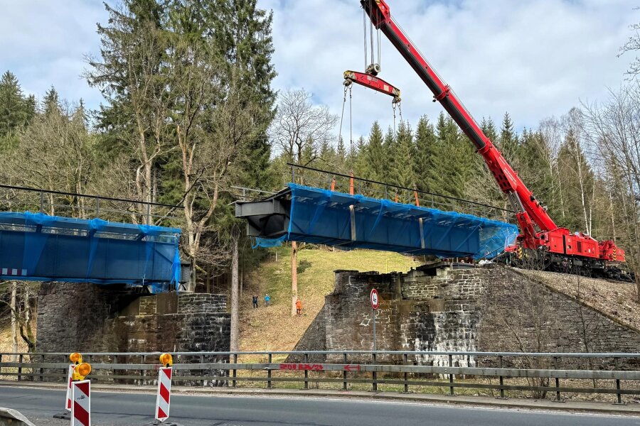 Zerstörte Eisenbahnbrücke im Erzgebirge soll repariert werden - Der aus Leipzig gekommene Eisenbahndrehkran hat einen Teil der Brücke ausgehoben.