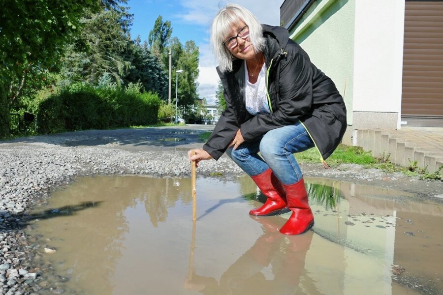 Zschopau: Vor dieser Pfütze fürchten sich Autofahrer - Margit Oettel misst mit dem Zollstock: Auch Tage nach einem Regen ist die Pfütze noch bis zu zehn Zentimeter tief. 