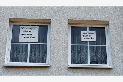 "Zwangsumsiedlung": Abriss von Häusern sorgt im Erzgebirge für Ärger - Mit handgeschriebenen Plakaten in seinen Stubenfenstern protestiert Karl-Heinz Hennig gegen den bevorstehenden Abriss des Hauses, in dem er wohnt.