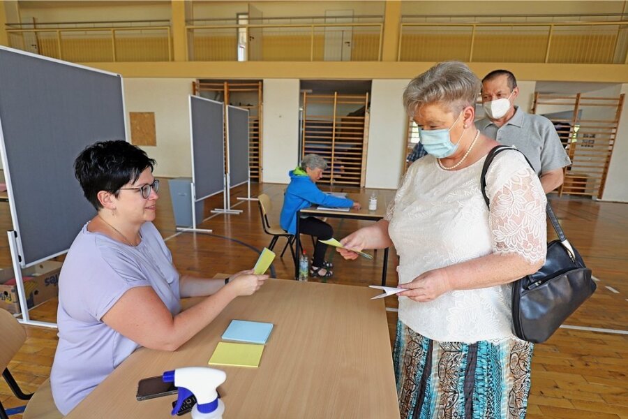 Zwei Wahlen an einem Tag in Freiberg: Wahlhelfer sind dennoch die Ruhe selbst - Wahlhelferin Jana Lützner (l.) händigt dem Ehepaar Bärbel und Harald Hellmich im Wahllokal in der Böhme-Grundschule die Wahlzettel aus. 