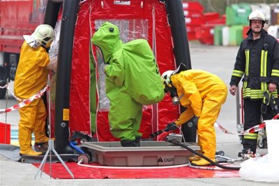 Schutzanzügen pumpen Feuerwehrmänner derzeit den Inhalt des Spezialbehälters um und reinigen anschließend den kontaminierten Laster